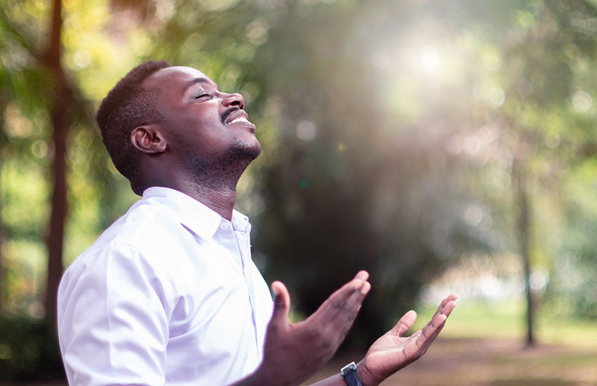 A man worshipping or praying alone while standing in the warm sunlight